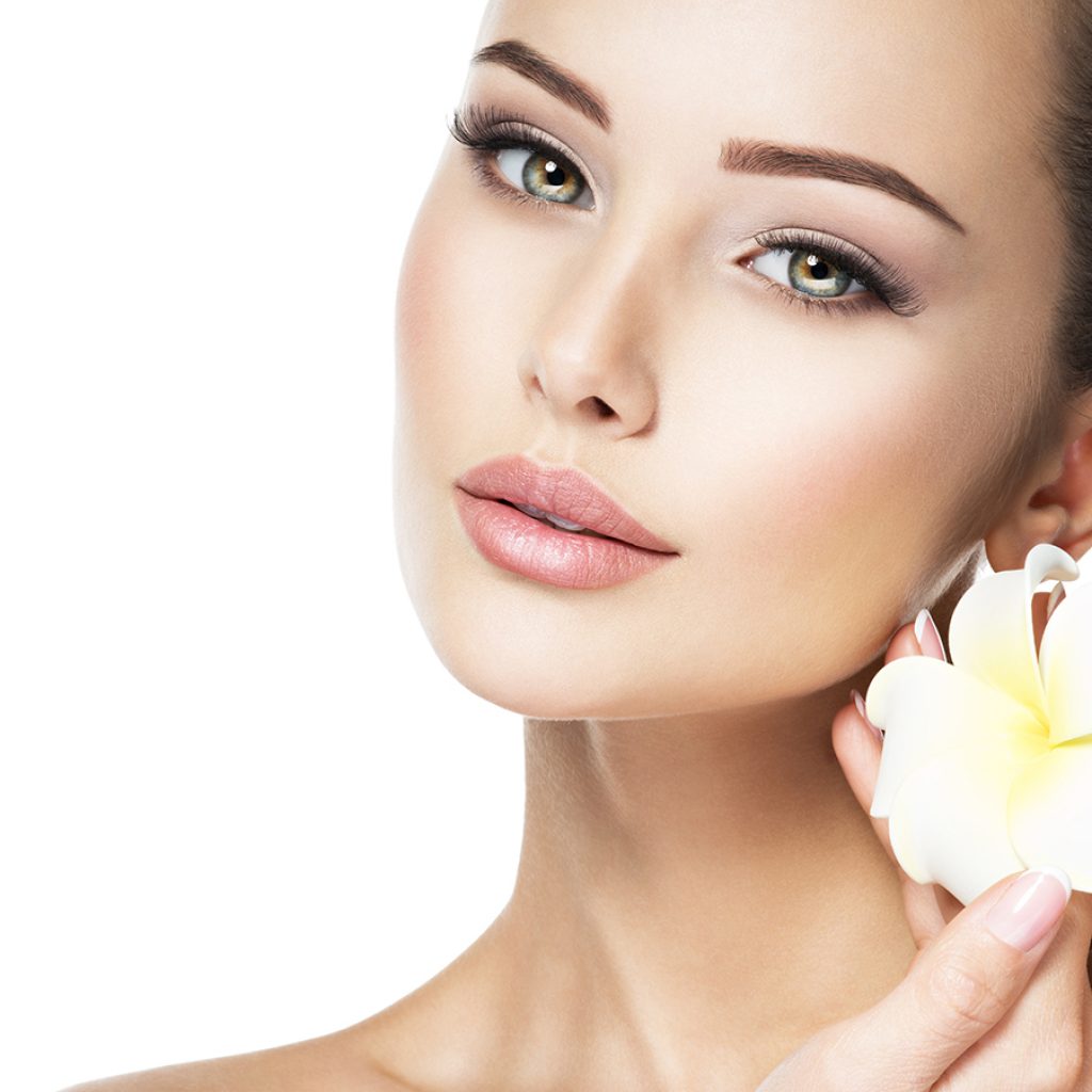 Beautiful face of young woman with flower. Clean healthy skin.